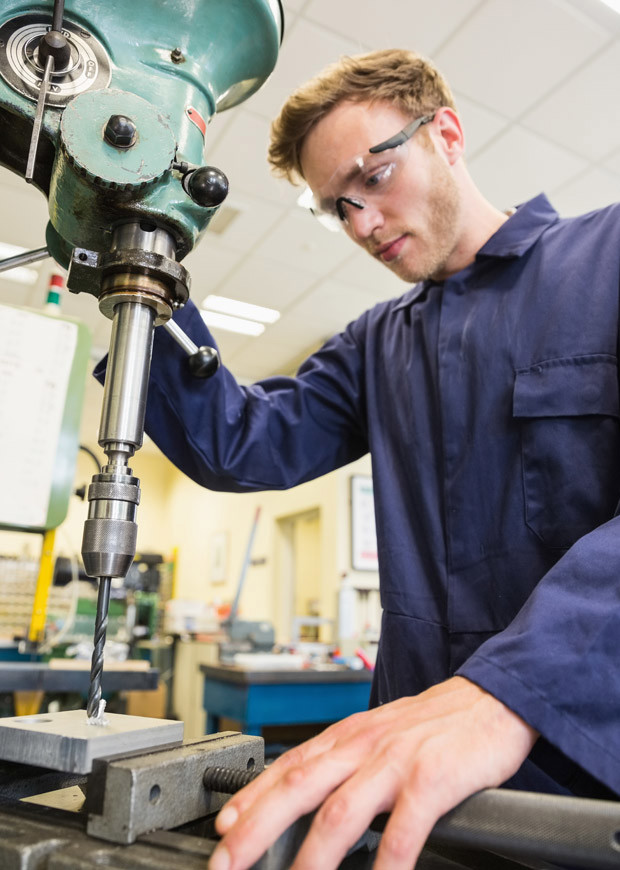 Student wearing goggles and using a drill