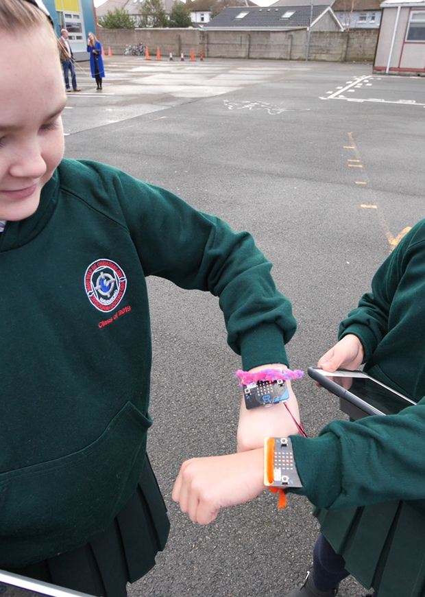 Two children showing their fitbits on wrists