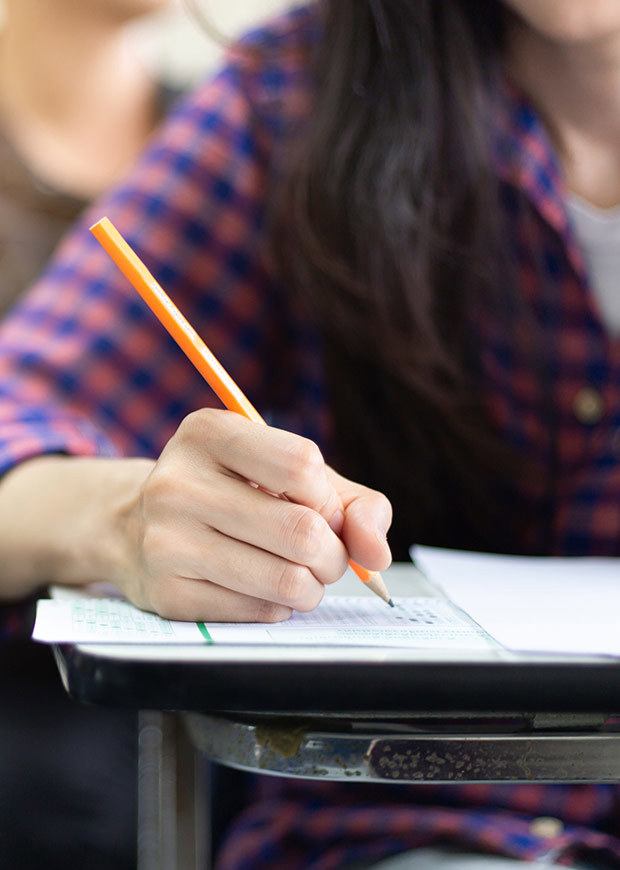 Close up of student writing in an exam, portrait shot