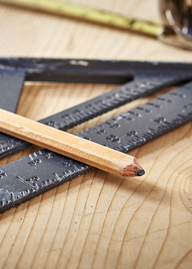 Set square, carpenters pencil and measuring tape sitting on wood
