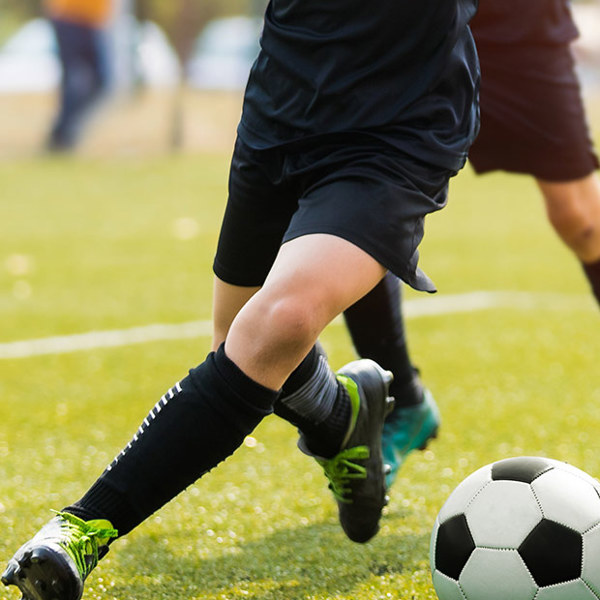 Portrait shot of students dribbling and tackling a soccer ball