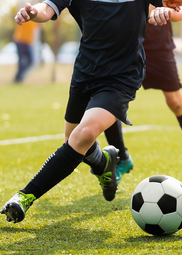 Portrait shot of students dribbling and tackling a soccer ball