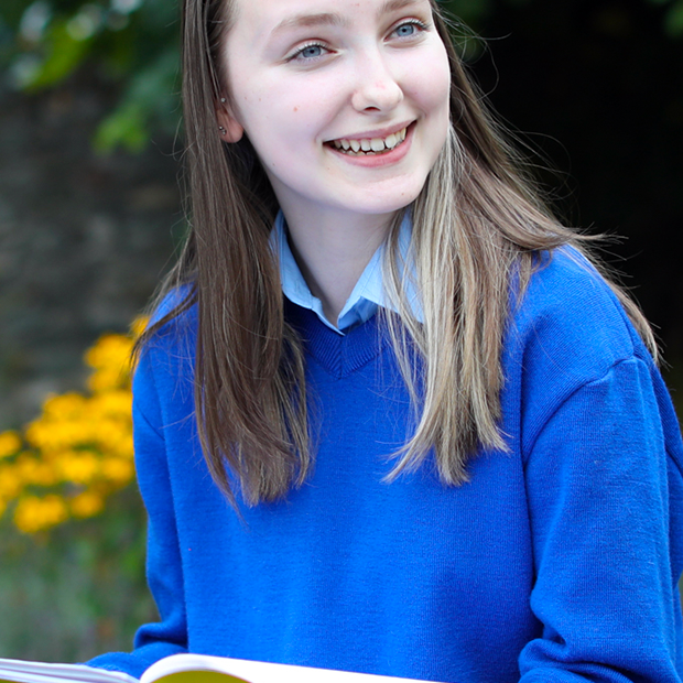 Happy schoolgirl reading from her book