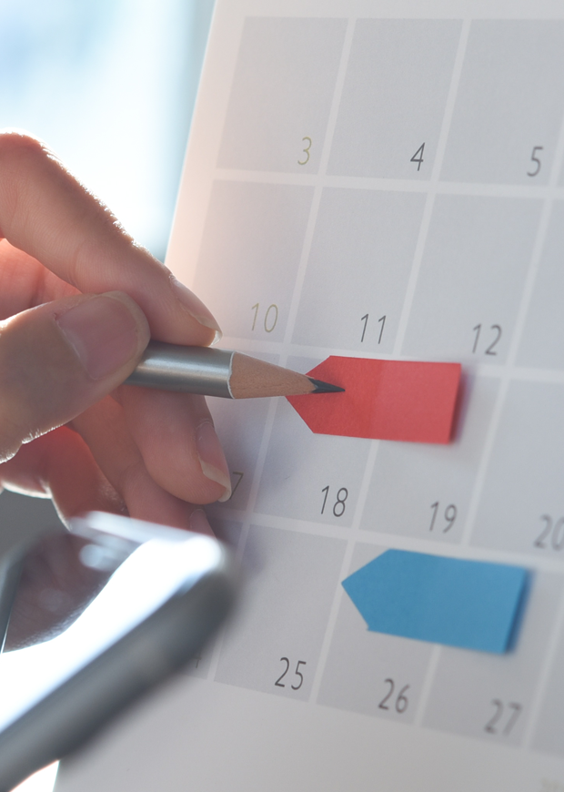 Hand pencilling in dates on a calendar
