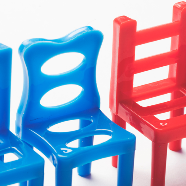 Row of blue plastic chairs with one red chair standing out