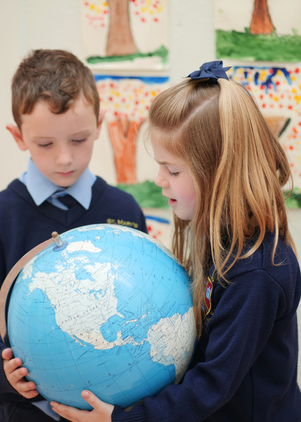 Boy and girl in a classroom looking at a globe
